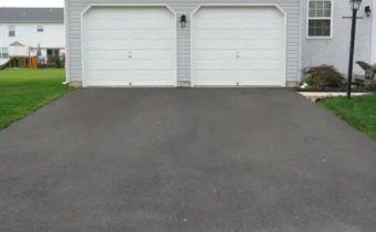 A double door garage with white doors at the end of a driveway