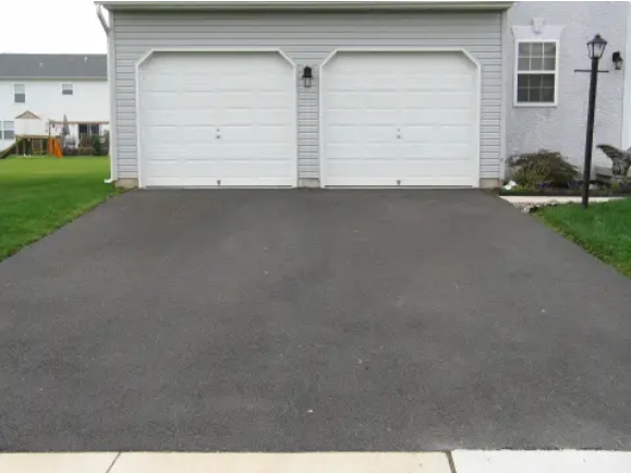 A double door garage with white doors at the end of a driveway